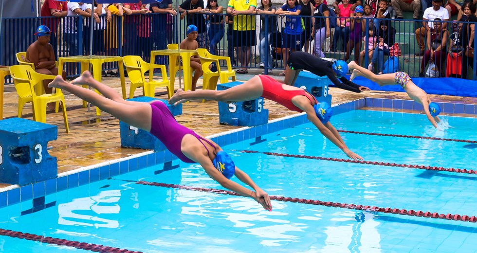 Crianças e jovens do projeto Nadando Primeiro competindo na piscina.